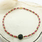 Bracelet en perles miyuki roses, marrons et dorées avec une pierre centrale en onyx. Le bracelet est posé sur un rond de vois écru. Des fleurs séchées en arrière plan. 