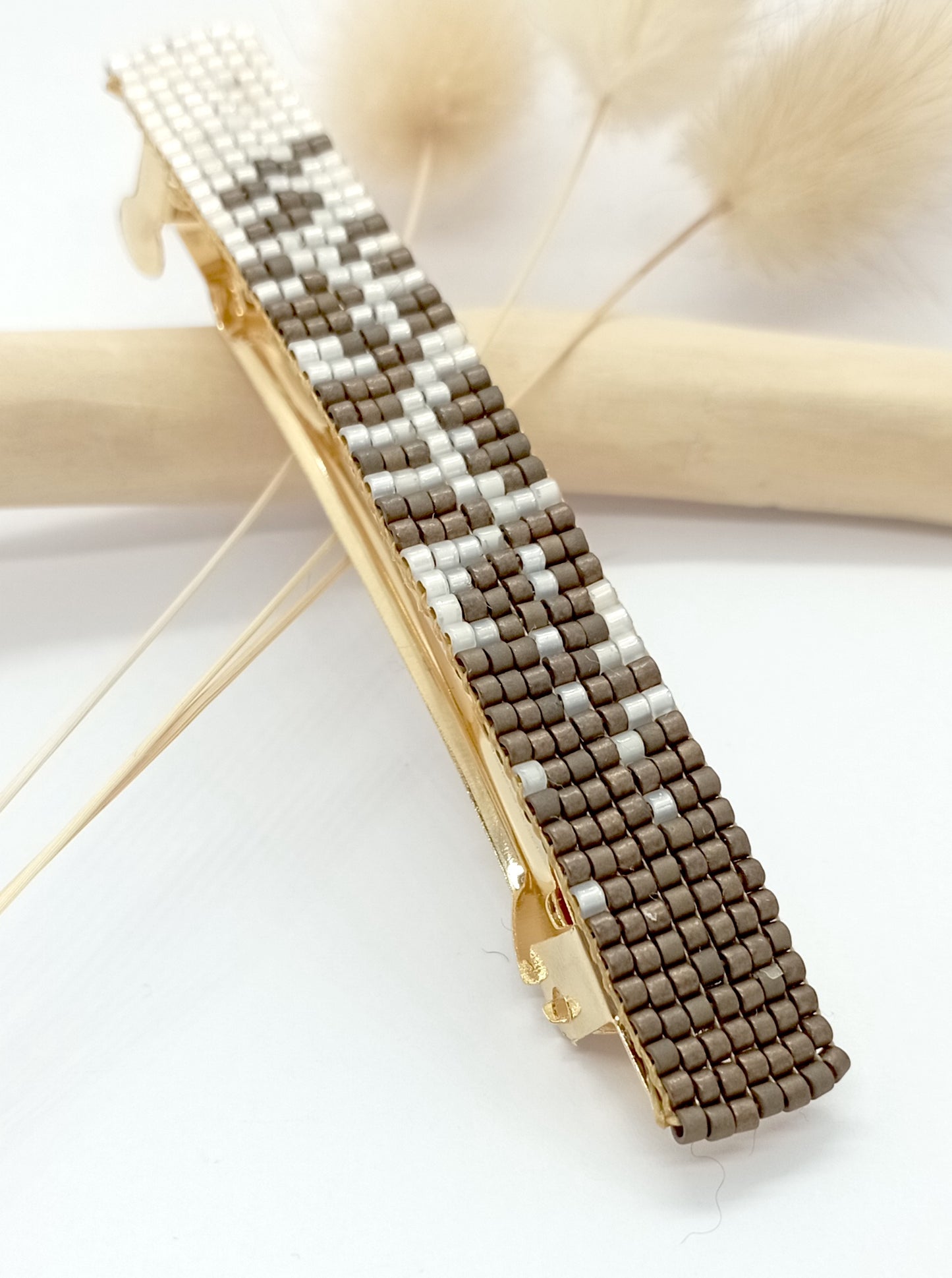 Barrette pour cheveux en métal et en perles tissées marrons et blanches.