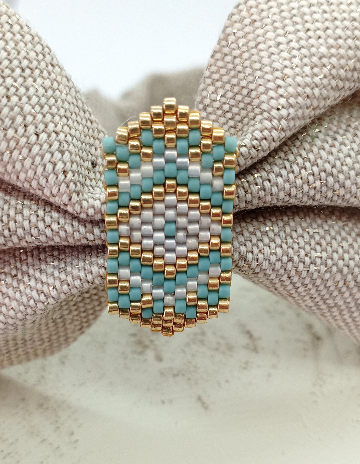 Bandeau en tissu beige irisé et broche en perles tissées bleues blanches et dorées