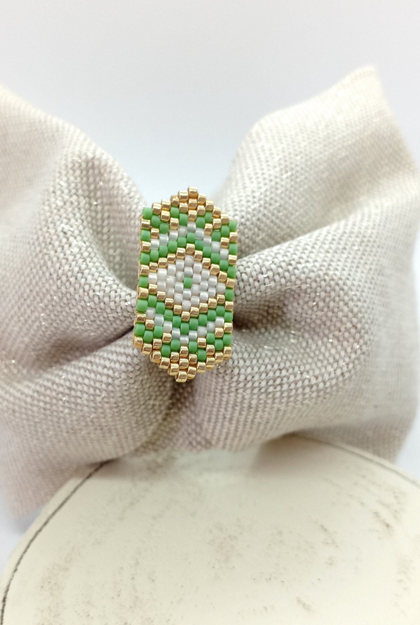 Bandeau en tissu beige irisé et broche en perles tissée verte, blanche et dorée