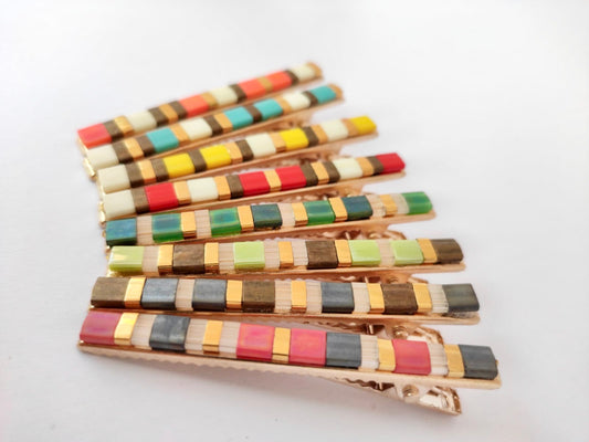 Barrettes crocodiles en métal dorée et en perles plates colorées sur un fond blanc. Carrées de couleurs