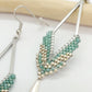 Boucles d'oreilles en acier argenté en forme de losange et perles miyuki tissées vert d'eau avec un sequin argenté. Posées sur fond blanc et bois clair